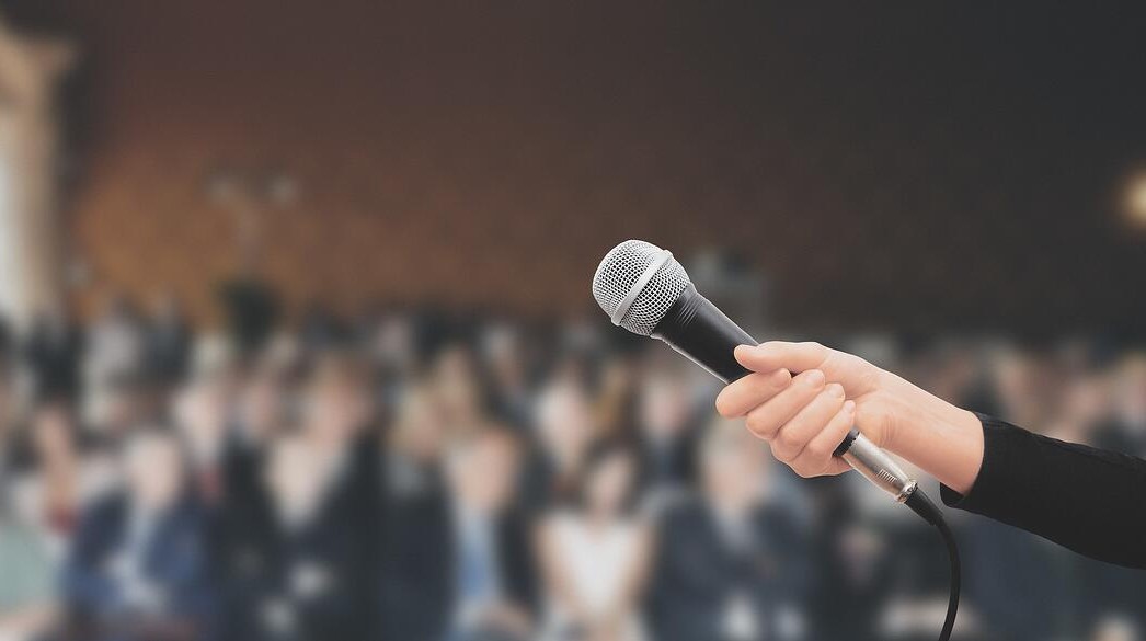 A hand with mic in public speaking stage
